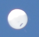 Le ballon vue presque de dessous, avec la nacelle qui se dessine nettement comme un petit rectangle sombre.